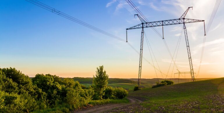 beautiful-wide-panorama-high-voltage-lines-power-pylons-stretching-through-spring-fields-group-green-trees-dawn-sunset-transmission-distribution-electricity-concept